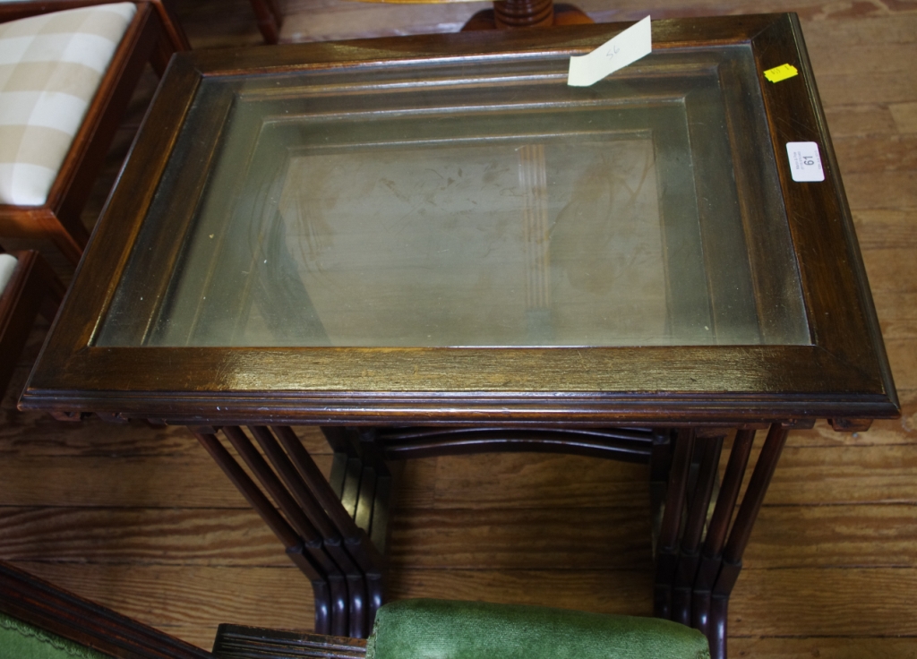 An Edwardian style mahogany nest of four tables with glass tops, with turned legs on trestle