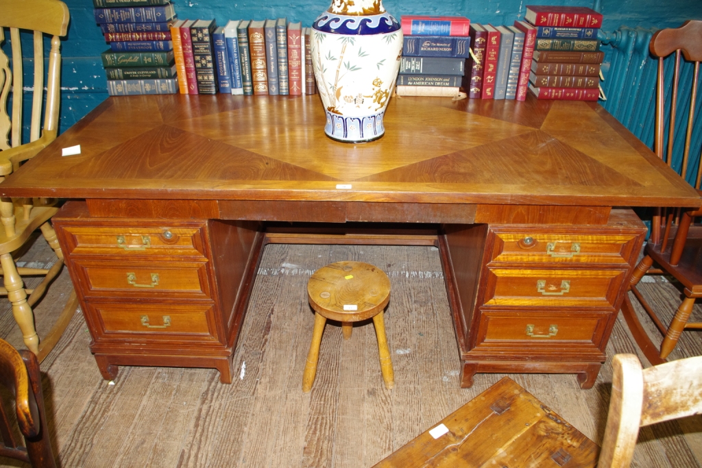 An early 20th century teak twin pedestal desk with parquetry design to the top, with six