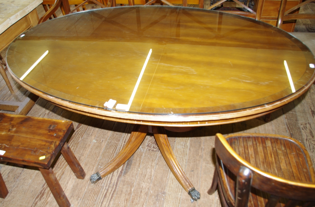 A Regency style mahogany oval dining table with reeded edge supported on a turned baluster shaped