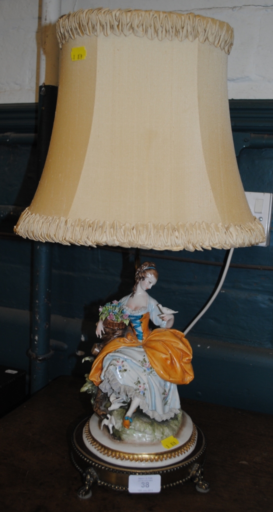 An early 20th century brass lamp adorned with a Neapolitan ceramic figurine of a lady with doves