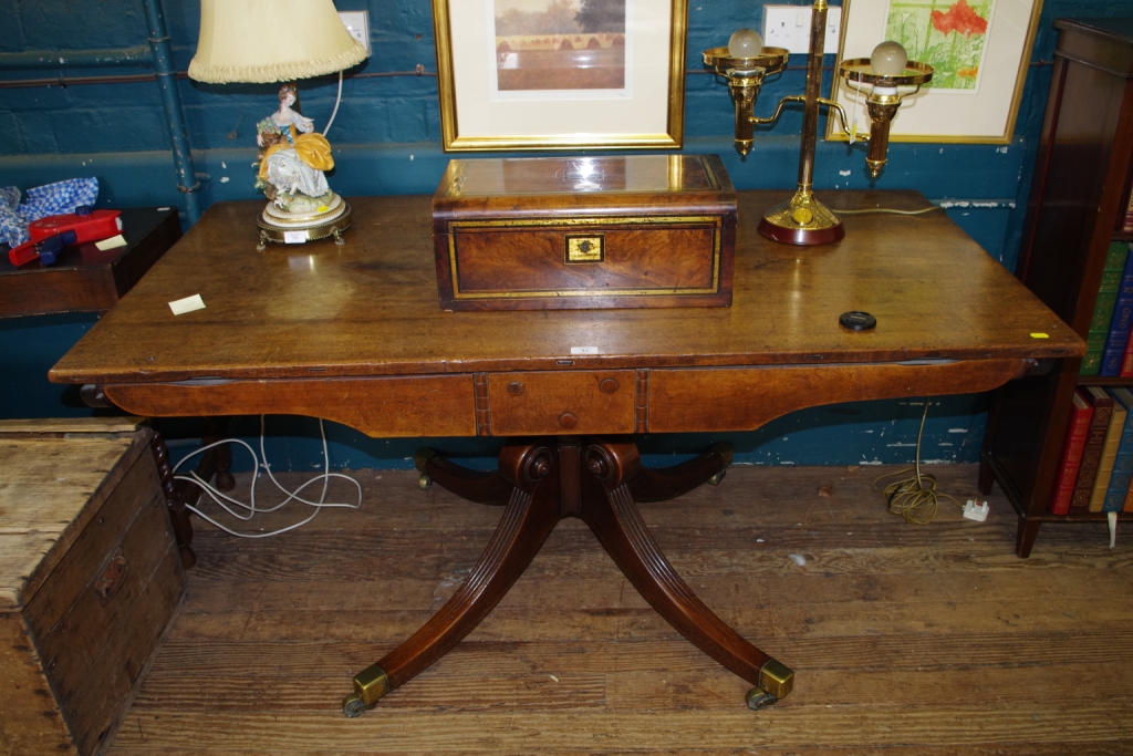 A Regency mahogany oblong shaped library table supported on a turned column and quadruped base