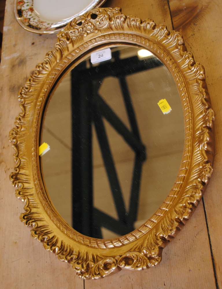 An oval shaped wall mirror with an elaborately carved gilt frame fitted for hanging