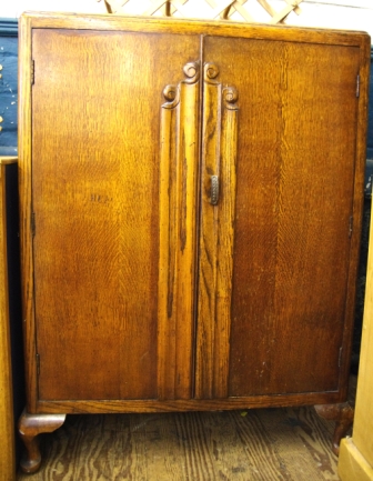 An early 20th century Continental style oak cabinet with shelved interior on cabriole legs