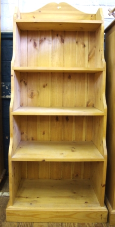 A pine bookcase with five cascading shelves on shaped base, measuring 145x57cm