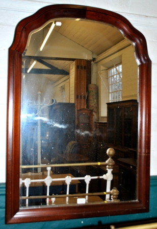 A large oblong bevelled glass mirror with dome scalloped top and stained wood frame