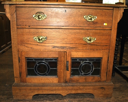 A late 19th century Arts and Crafts style chest with shaped top, two drawers under, supported by two