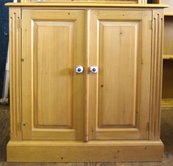 An attractive pine two door cupboard with shaped top, shelved interior with porcelain fittings and