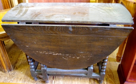 An oak stained gate legged table with shaped legs and stretcher supports