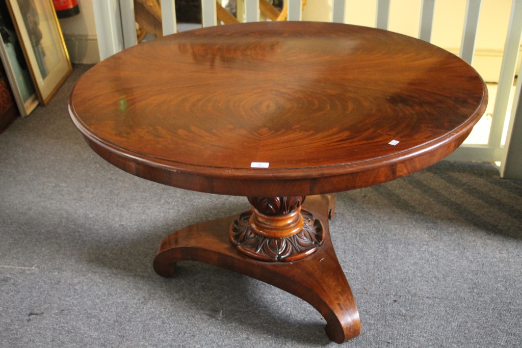 A VICTORIAN MAHOGANY CIRCULAR DINING TABLE with tip-up top on a carved column and triform base,