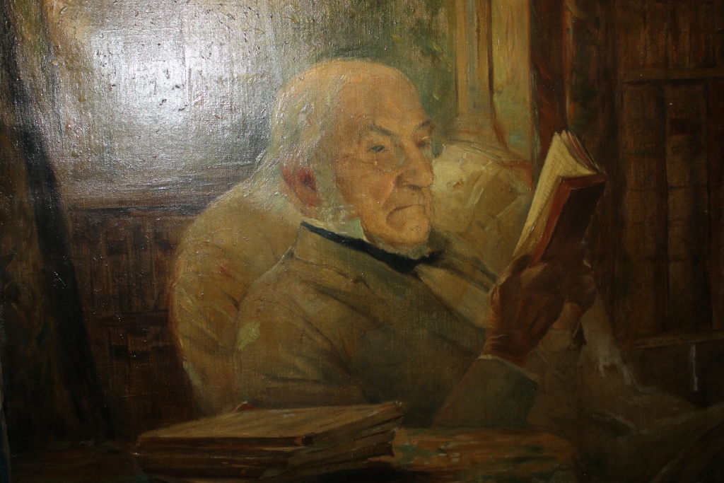 20th Century English School A study of an older gentleman reading a book at his desk, oils on