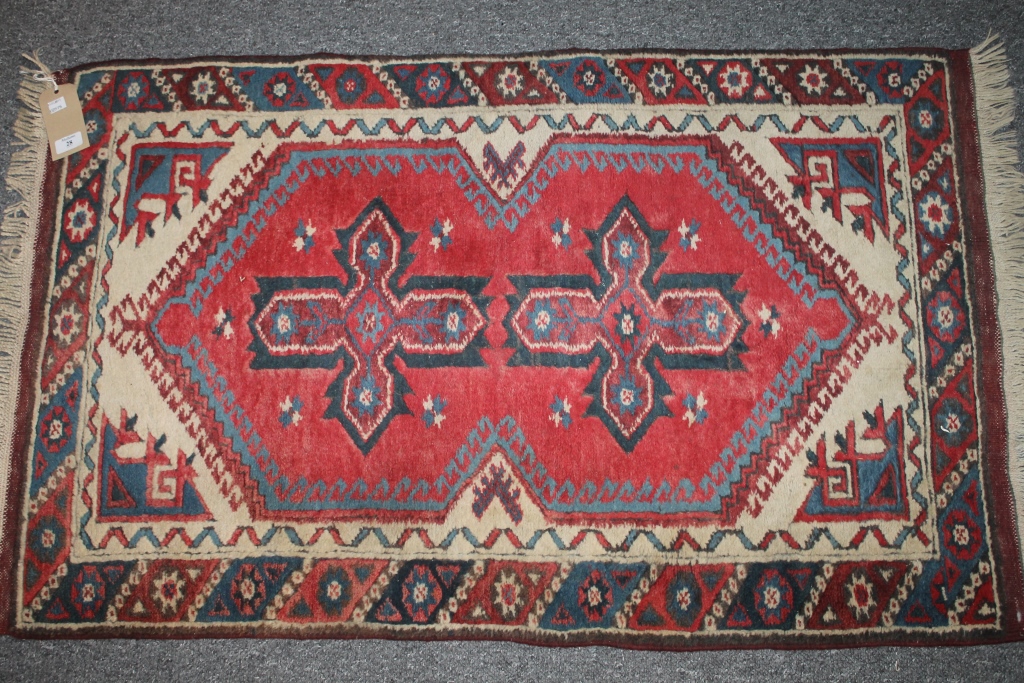 A PAKISTAN RED GROUND RUG with two central star designs, 120cm x 74cm and another similar rug