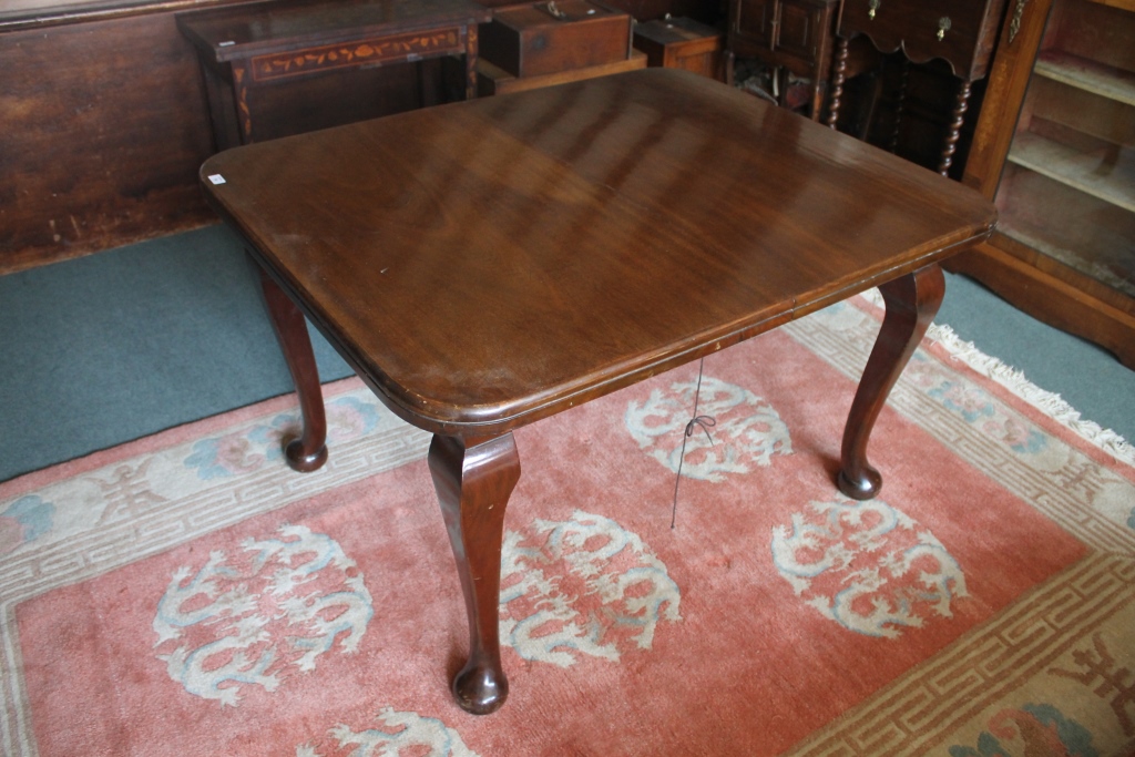 AN EDWARDIAN MAHOGANY EXTENDING DINING TABLE with one extra leaf on large cabriole supports, 180cm x