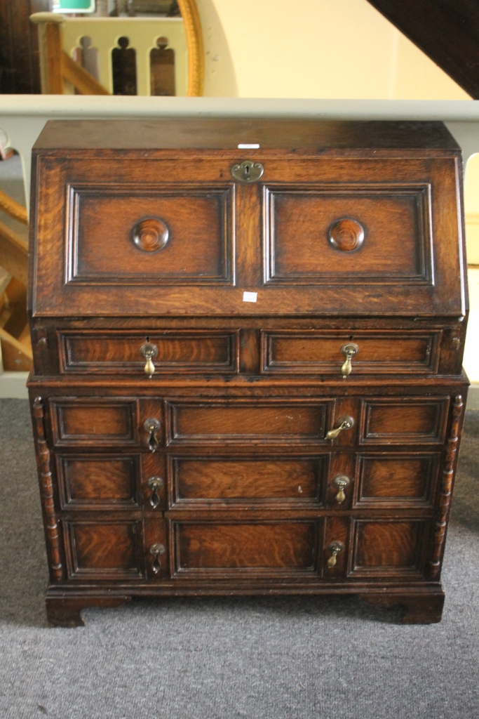 AN OAK CAROLEAN STYLE BUREAU with fall front, fitted two short and three long drawers below, 82cm