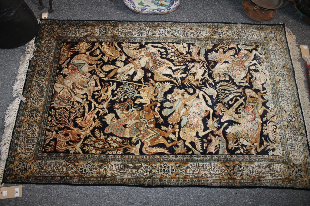 A PERSIAN SILK RUG with central panel with hunting scenes within a panelled border with Islamic