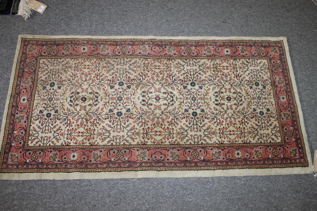 A TUNISIAN BEIGE GROUND SMALL RUG with allover foliate decoration, 140cm x 72cm