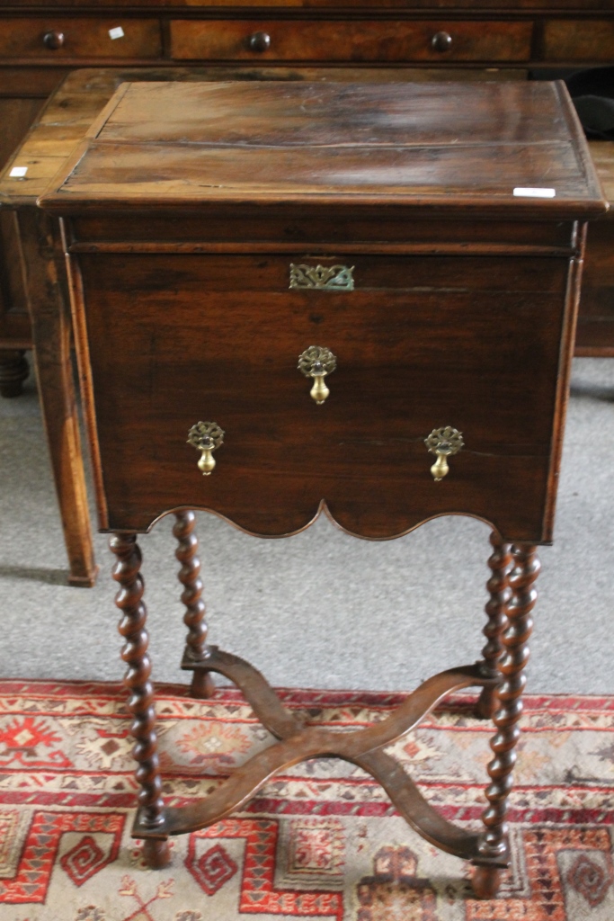 AN ANTIQUE WALNUT BOX on stand with lift up top, pear drop handles and `X` shaped stretcher, 55.