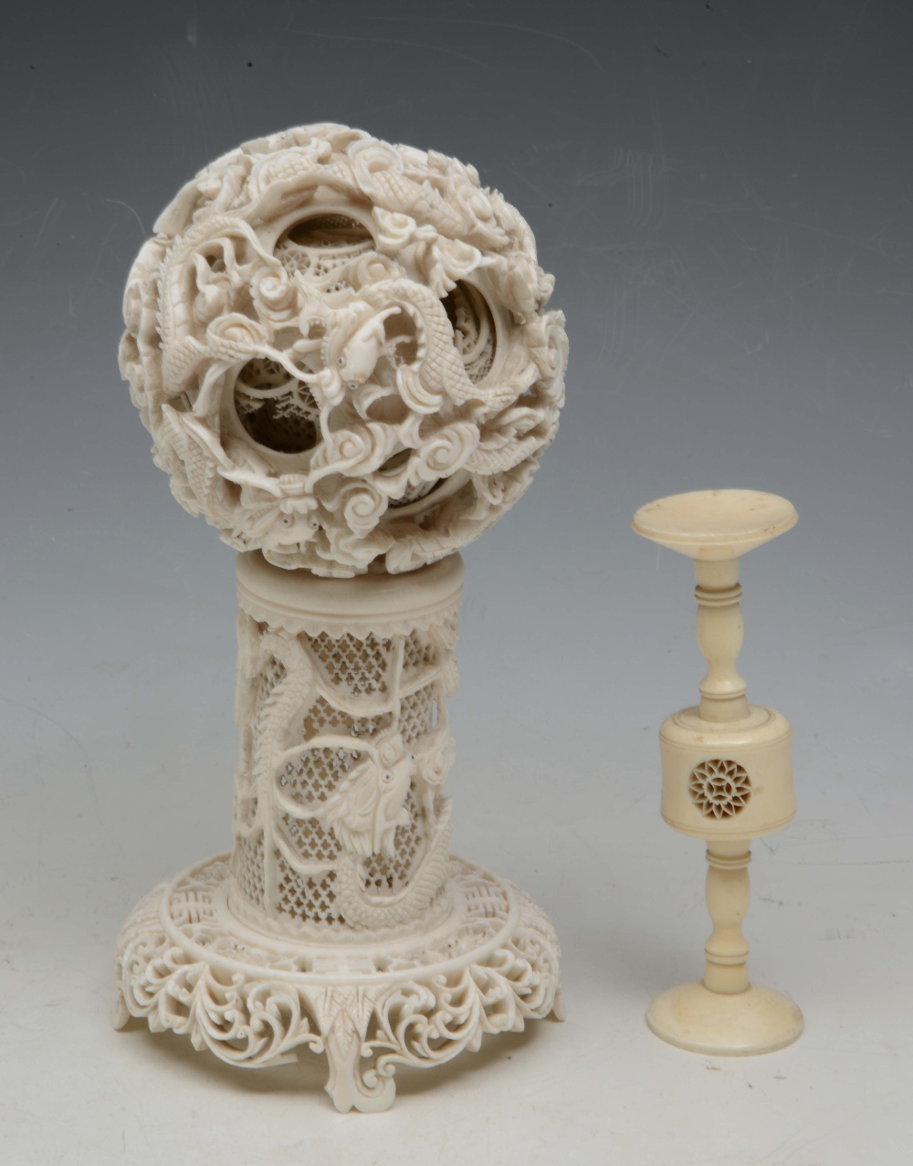 A CHINESE IVORY CONCENTRIC BALL, pierced and carved dragons and swirling clouds on pedestal stand,