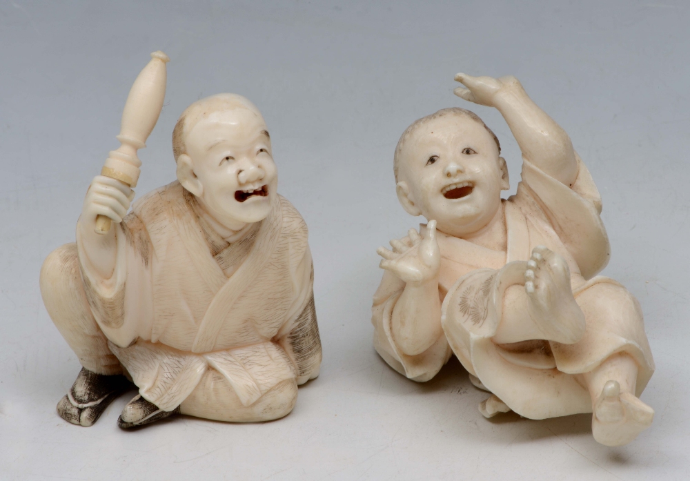 A JAPANESE IVORY OKIMONO, seated man with rolled umbrella, and a figure of a boy playfully laying