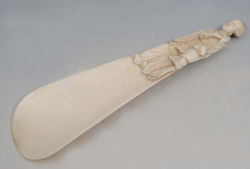 A CHINESE CANTON IVORY SHOE HORN, the handle carved with court lady and youth figure holding a coral