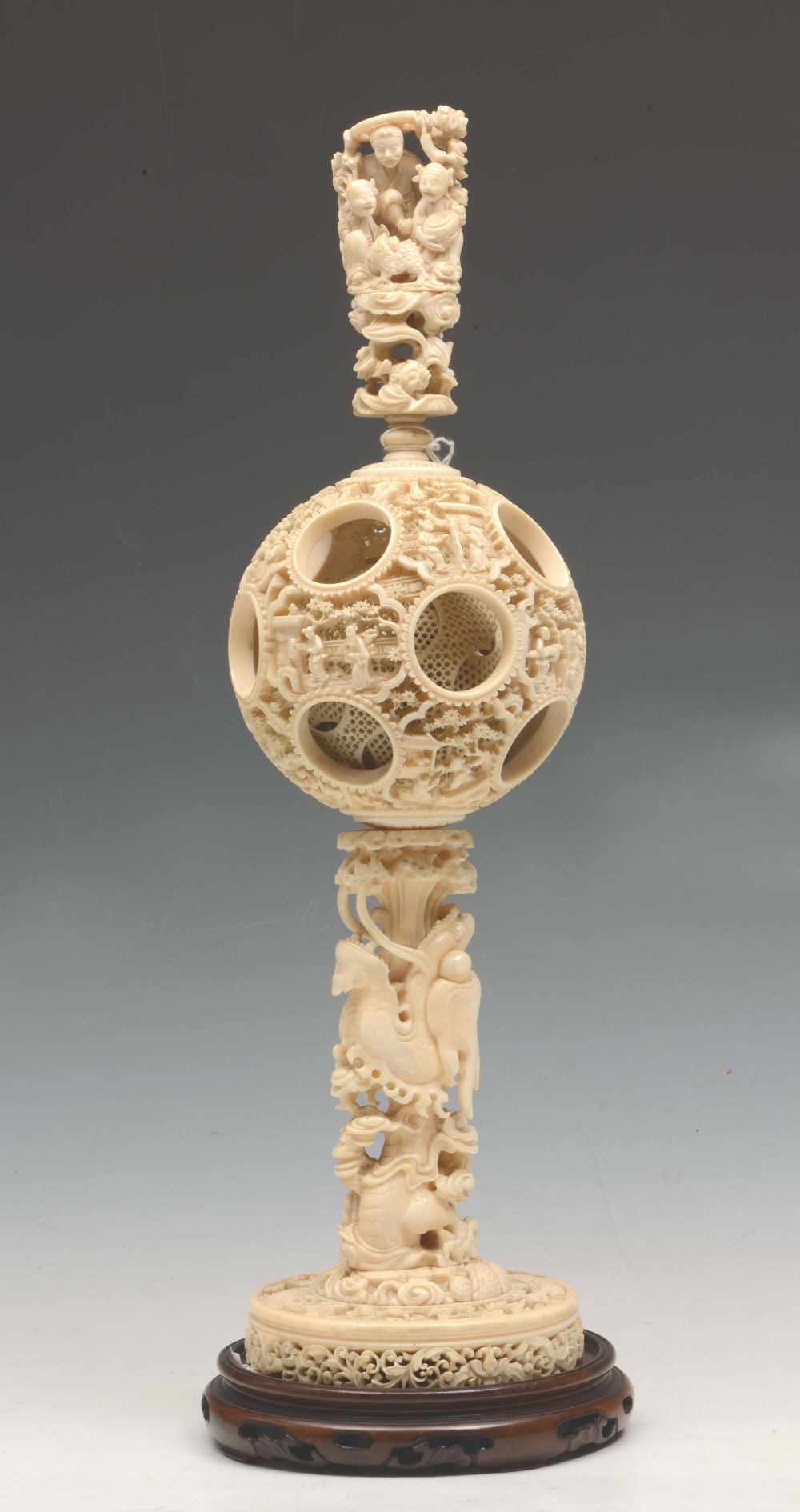 A CHINESE CANTON CARVED IVORY PUZZLE BALL on stand, having a tapering finial carved with three