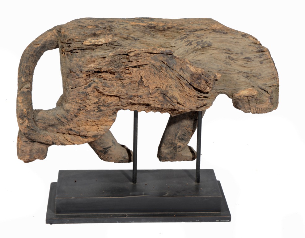 AN EASTERN CARVED SOFTWOOD FIGURE of a wild animal (now very weathered), 29" long, 15" high