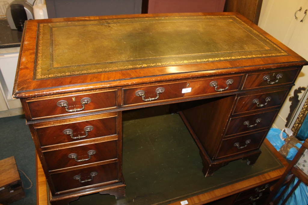 A REPRODUCTION MAHOGANY KNEE HOLE PEDESTAL DESK fitted with nine drawers, 48"