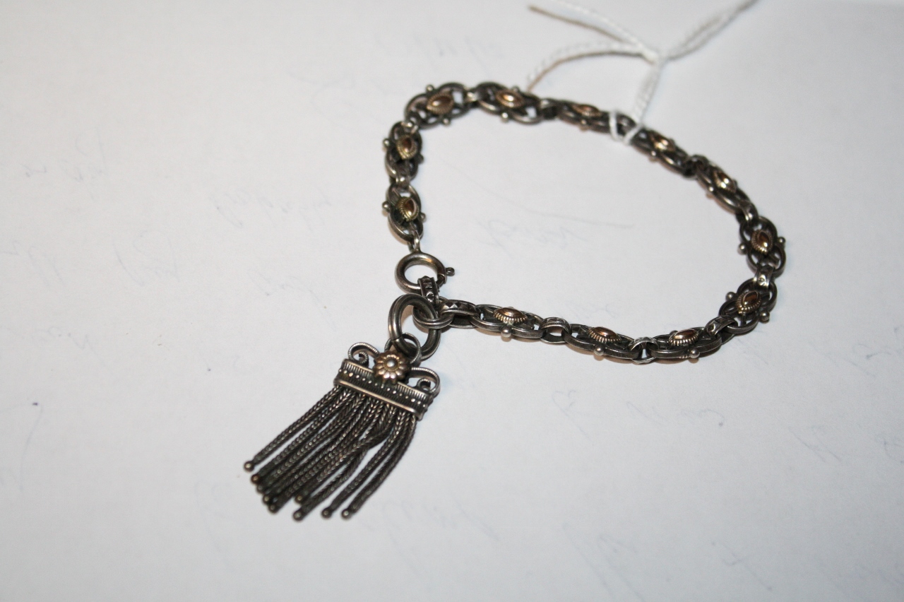 A CONTINENTAL SILVER AND GOLD OVERLAID BRACELET with figure of eight links and attached tassel