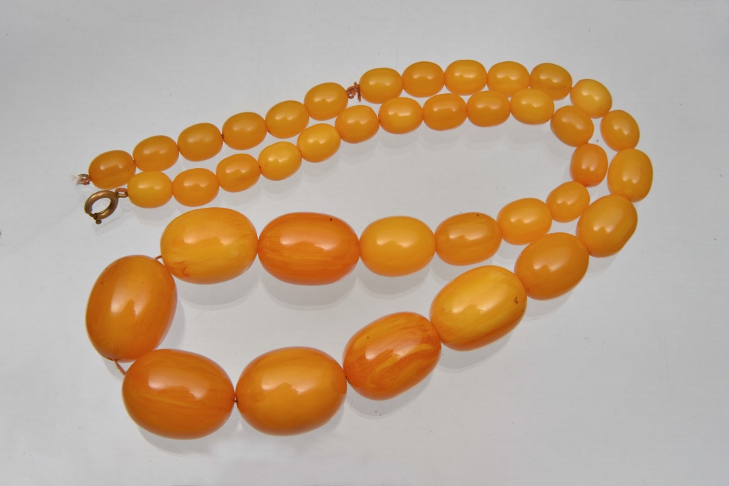 A GRADUATED FAUX AMBER BEAD NECKLACE, 23" long