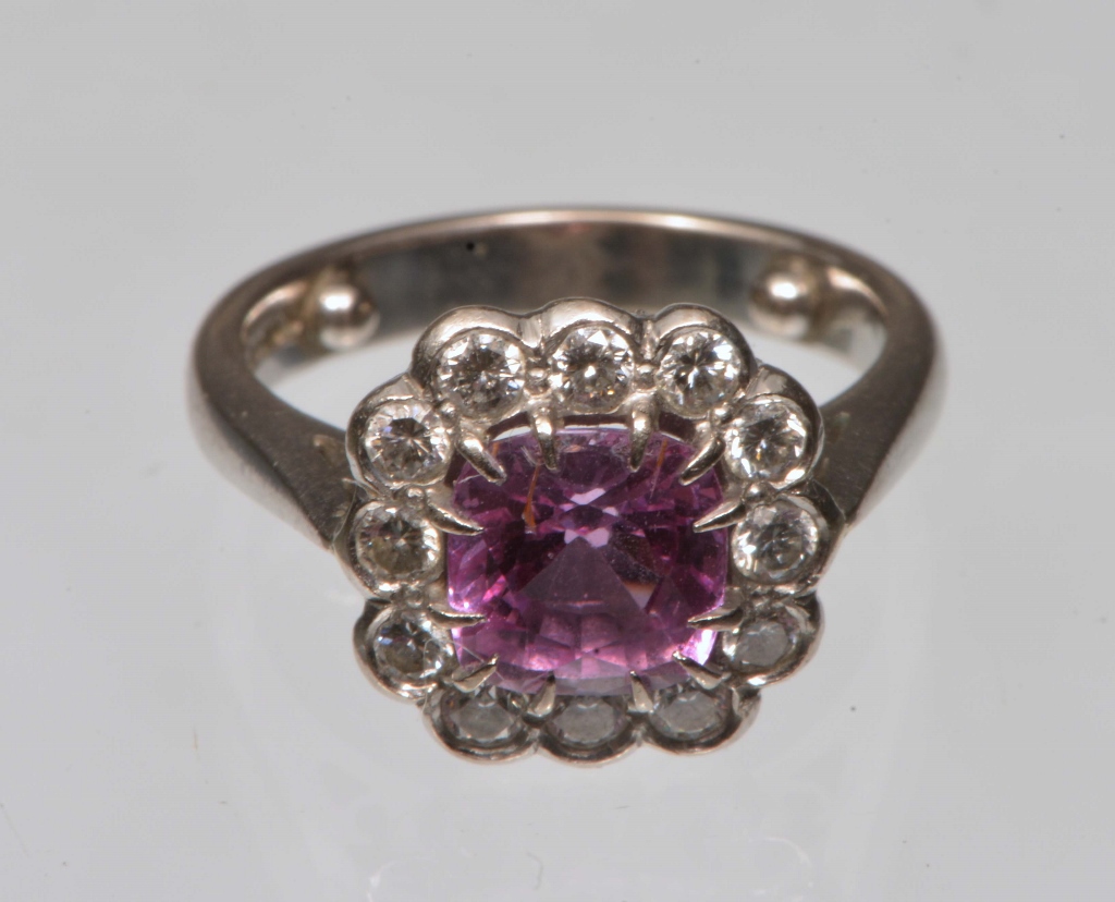 A PINK SAPPHIRE AND DIAMOND SET DRESS RING, claw set cushion cut sapphire surrounded by twelve