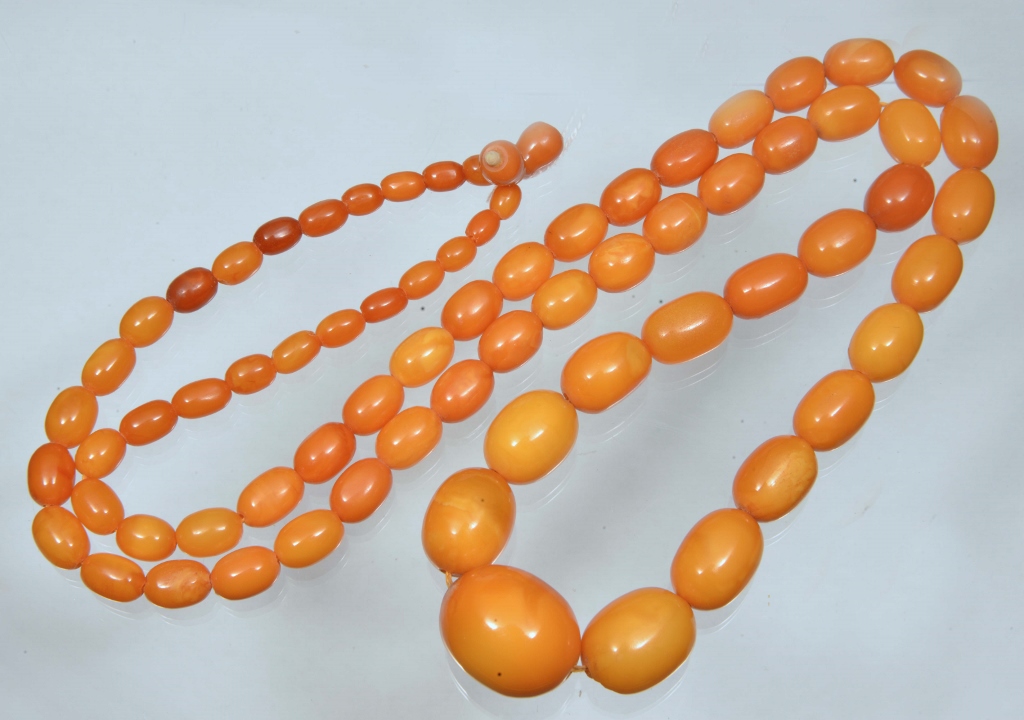 A GRADUATED OVAL AMBER BEAD NECKLACE, egg yolk colour, 36" long, largest bead 21mm wide down to 5.