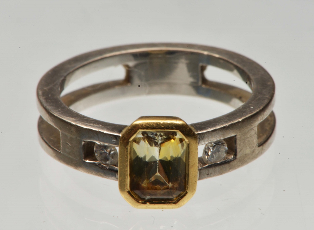 A CONTEMPORARY YELLOW SAPPHIRE AND DIAMOND SET RING, emerald cut mounted in a yellow gold rub over