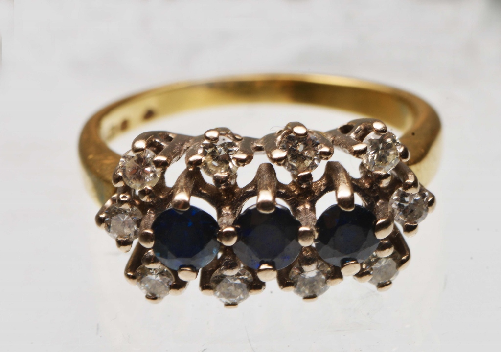 A SAPPHIRE AND DIAMOND DRESS RING, three claw set sapphires surrounded by ten diamonds in a row in