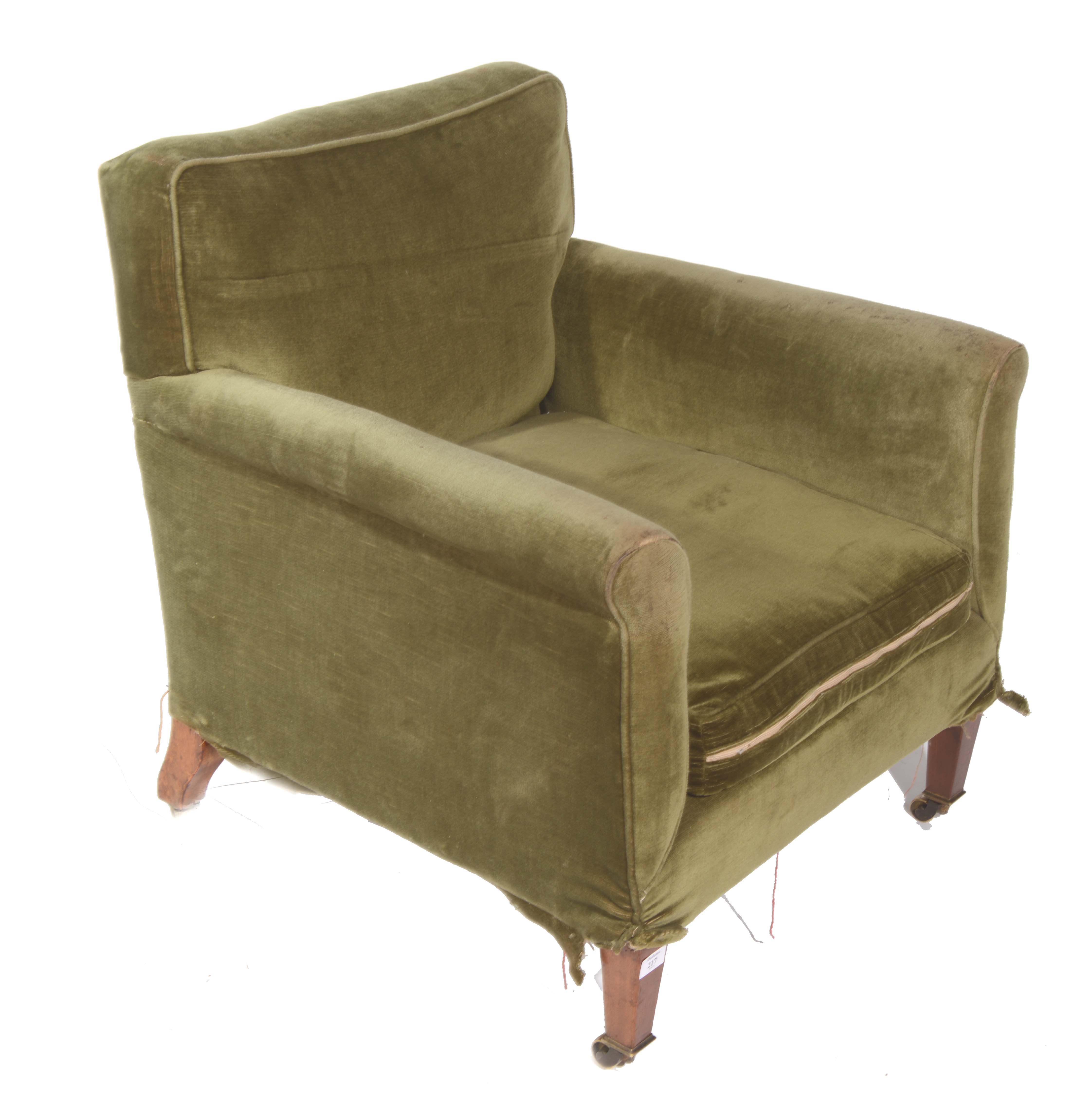 A LOW ARMCHAIR upholstered in green material on four square tapering legs and brass castors