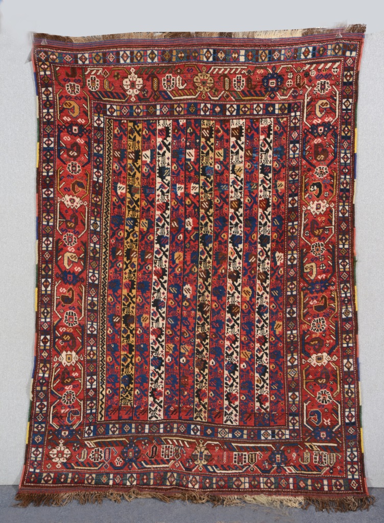 A KHAMSEH RED GROUND `CANE` RUG, the twelve central vertical panels alternating decoration and