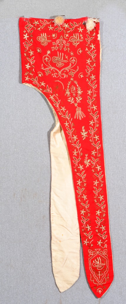 A TURKISH RED GROUND HOOD OR STOLE with gold and white thread trailing foliate decoration and silk