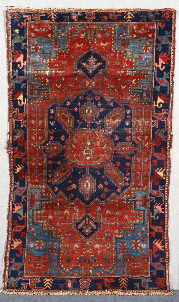 A KURDISH RUST GROUND RUG with a central blue ground medallion and stylised border, 2.02m x 1.19m