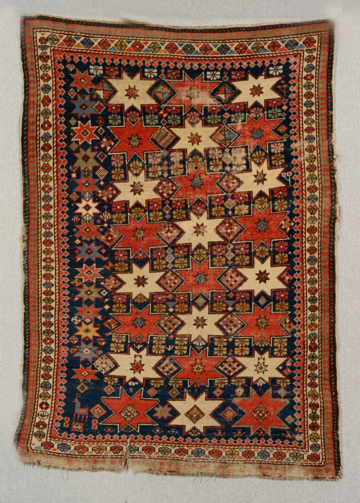 AN OLD SHIRVAN RUG decorated rows of stars and geometric designs, 1.54m x 1.09m