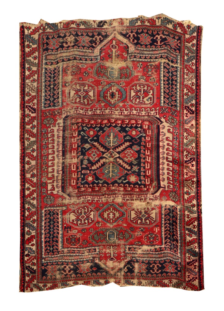 AN OLD PERGAM RUG decorated with stylistic geometric designs on a red ground, 2.26m x 1.79m