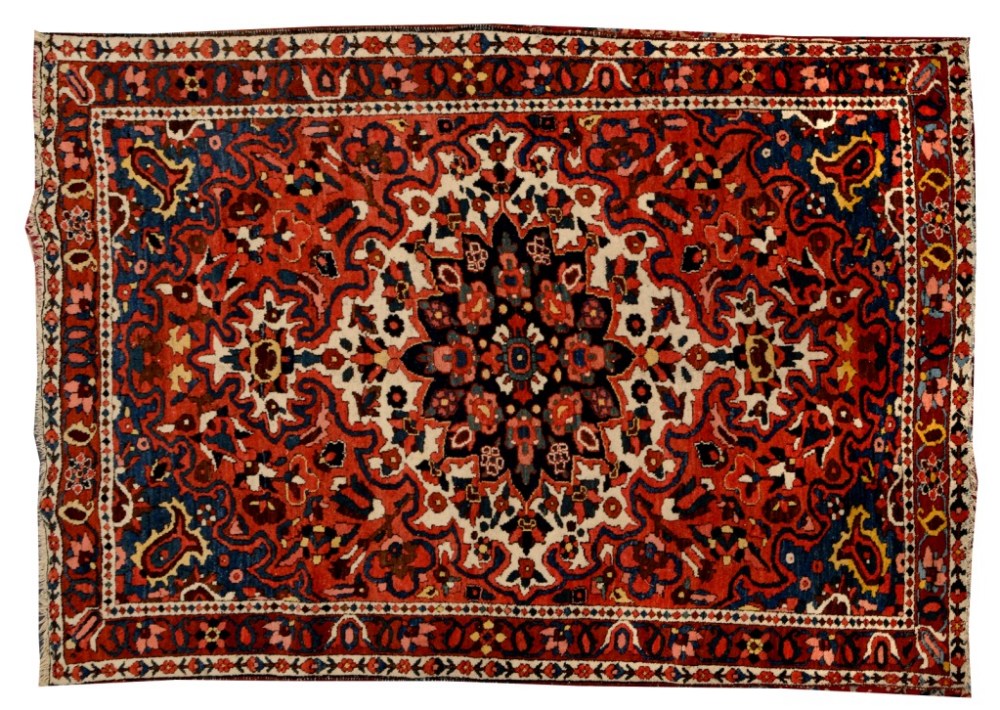 A BAKHTIARI RED GROUND RUG decorated a central large white ground medallion within a triple foliate