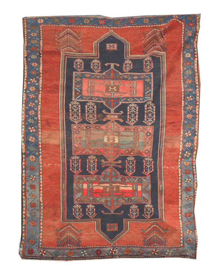 A KASAK RED GROUND RUG, the central blue ground panel decorated with hooked medallions within a