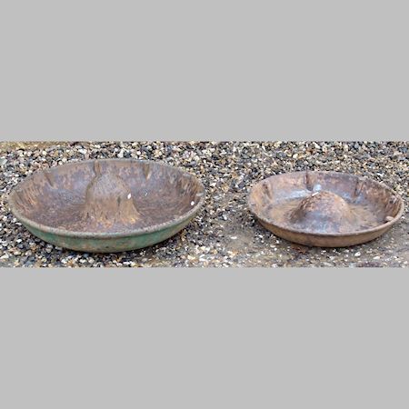 Two circular cast iron pig troughs