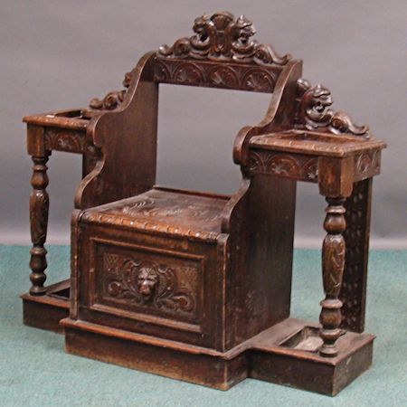 A Victorian heavily carved oak hallstand, having an open back, above a hinged seat and panelled