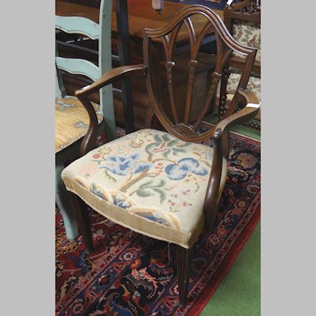 A George II carved mahogany open armchair, with a shield back and tapestry seat