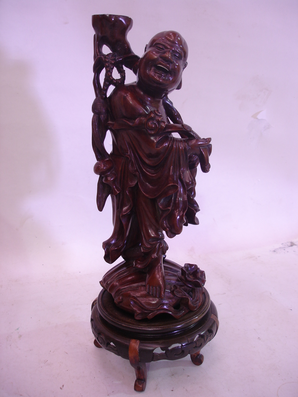 An Oriental carved hardwood figure of an immortal raised on an associated stand. 14" high