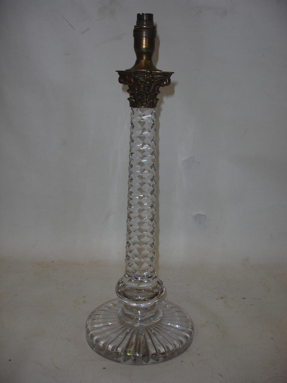 An early 20th century cut glass lamp with Corinthian brass capital. 21" high (Three small chips to