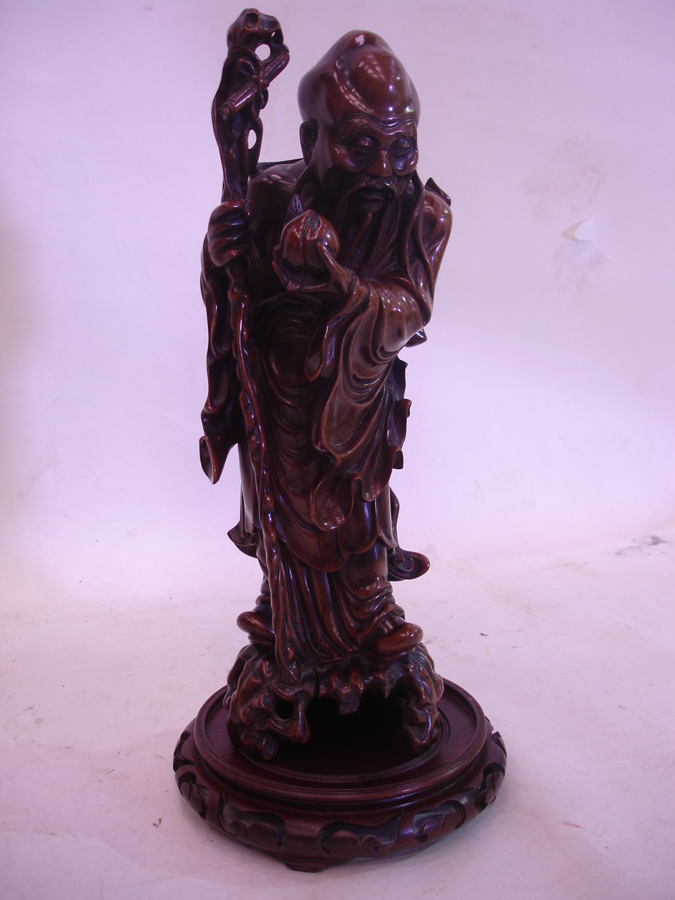 An Oriental carved hardwood figure of a sage, with associated stand. 14" high (Split to front and