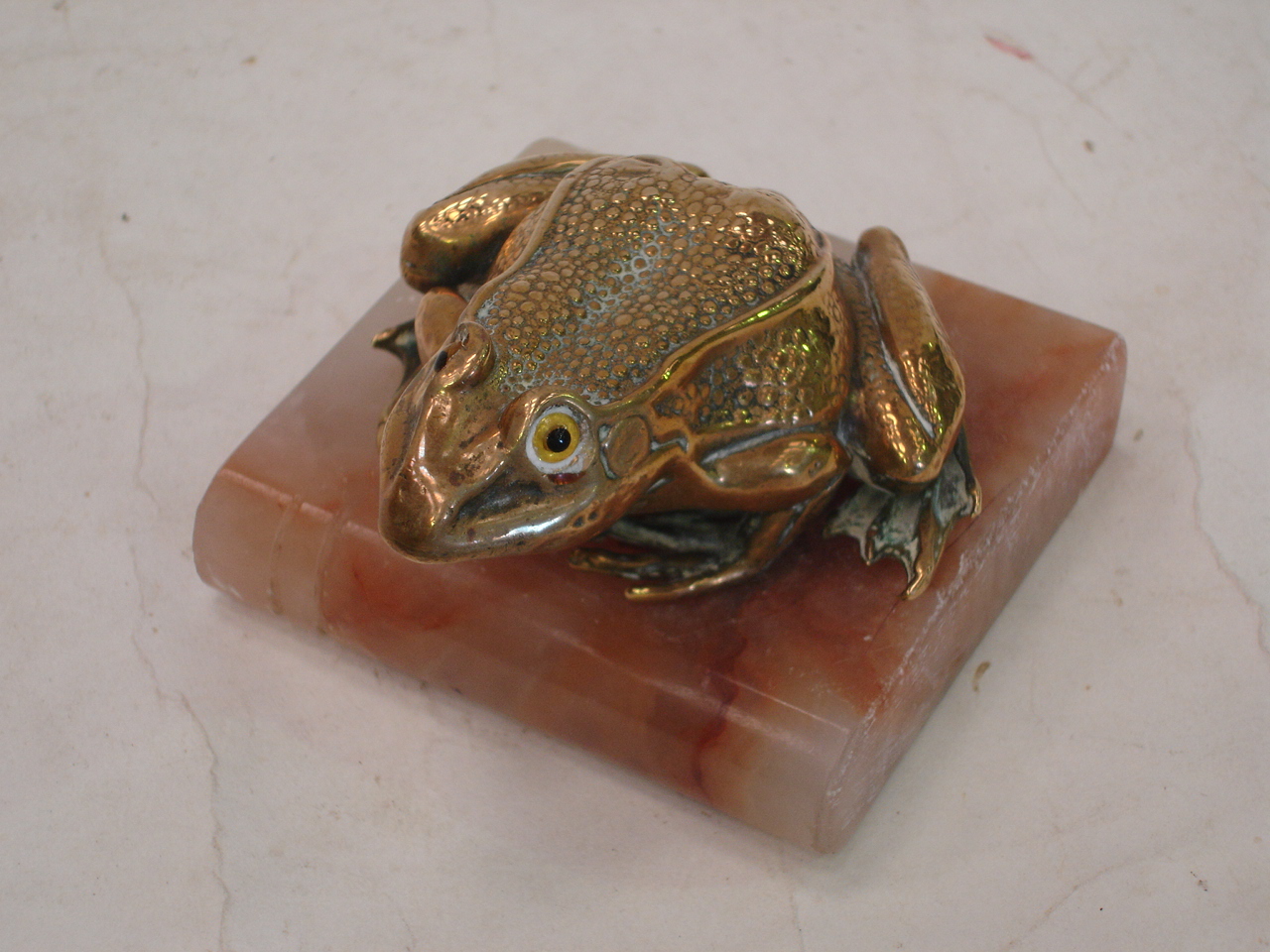 A cast brass frog desk weight with glass eyes raised on an onyx base. 3 ½" wide