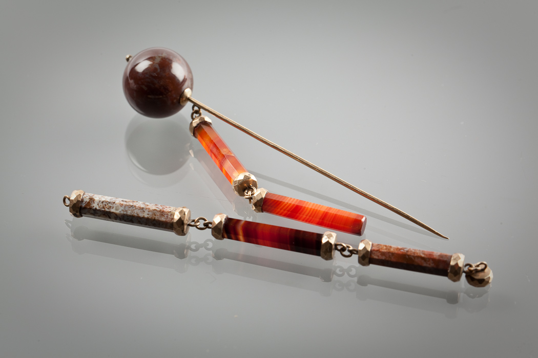 SCOTTISH VICTORIAN HARDSTONE PIN mounted with a brown agate, 10cm long, with attached chain formed