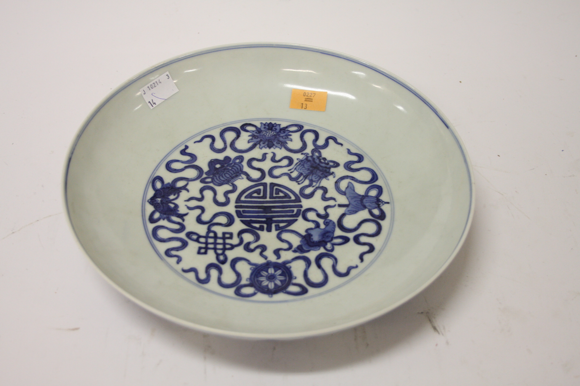 A CHINESE BLUE AND WHITE CIRCULAR DISH, 
decorated with ribbons, fish, flowers and urns, bares blue