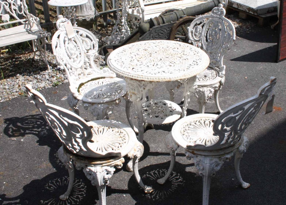 A SET OF FOUR HEAVY CAST IRON PATIO CHAIRS,
each with a pierced scroll back and circular pierced